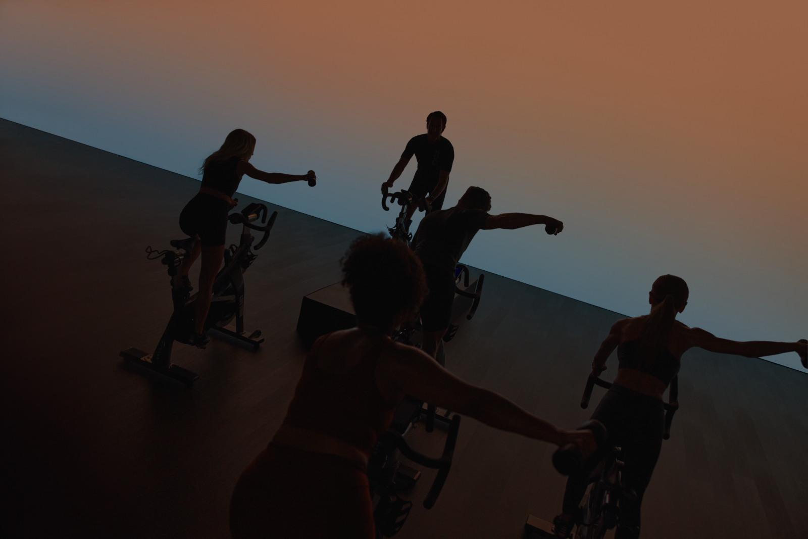 EDG spin class riding in silhouette, riders with their right arms extended holding a weight