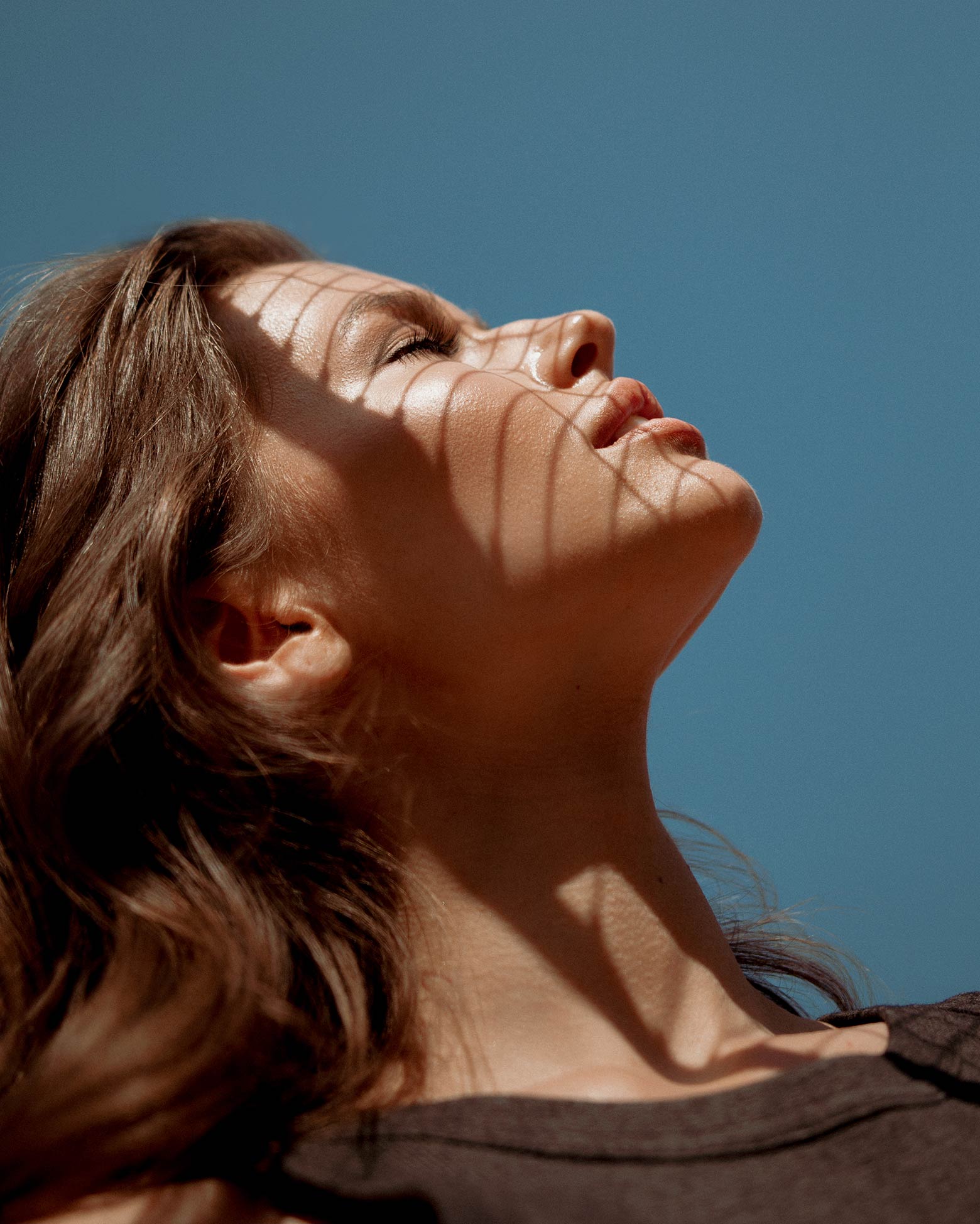 A Life Time member in profile with their face tilted up to the sun, striped with shadows