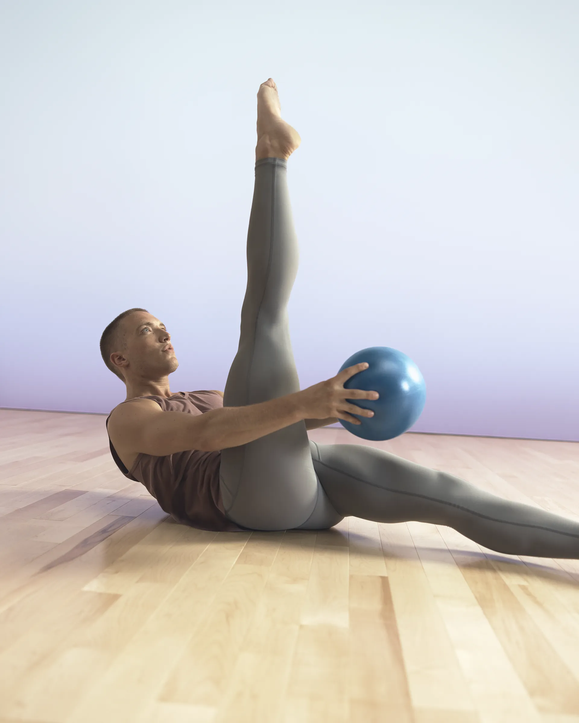 Life barre class participant on floor with leg raised using ball at Life Time