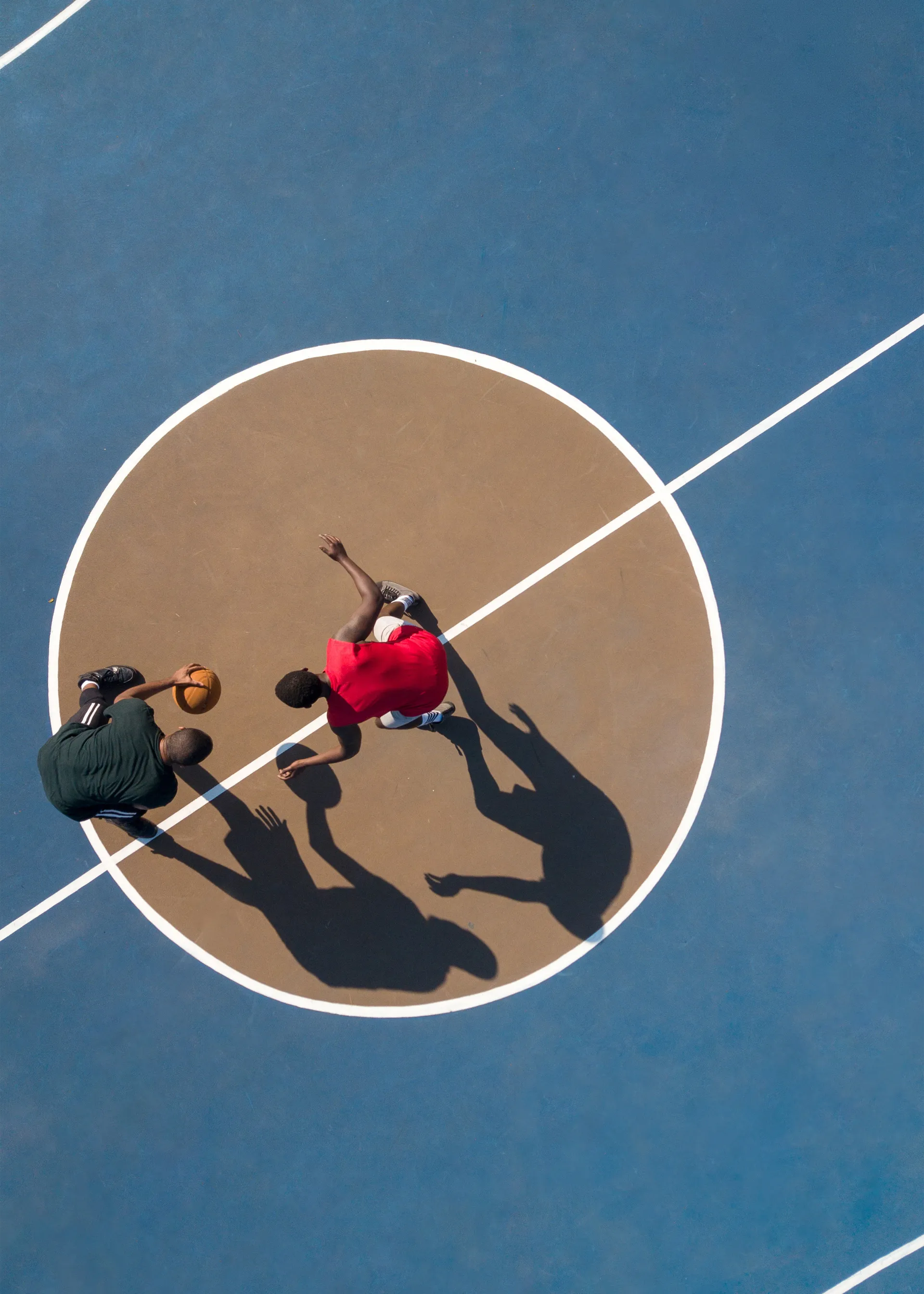 An aerial view of two basketball players on an outdoor court.