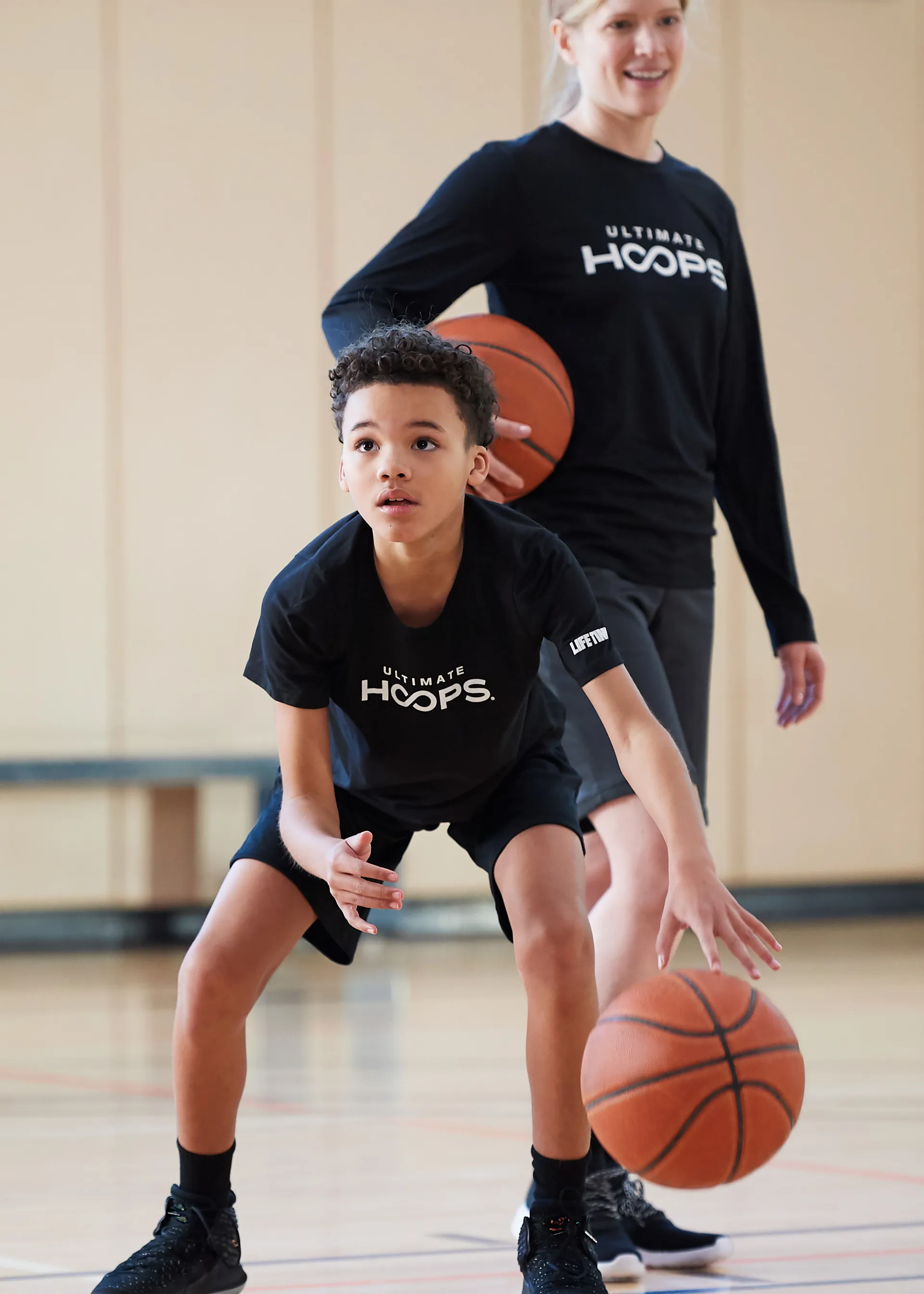 Two young basketball players wearing Life Time tee shirts playing basketball.
