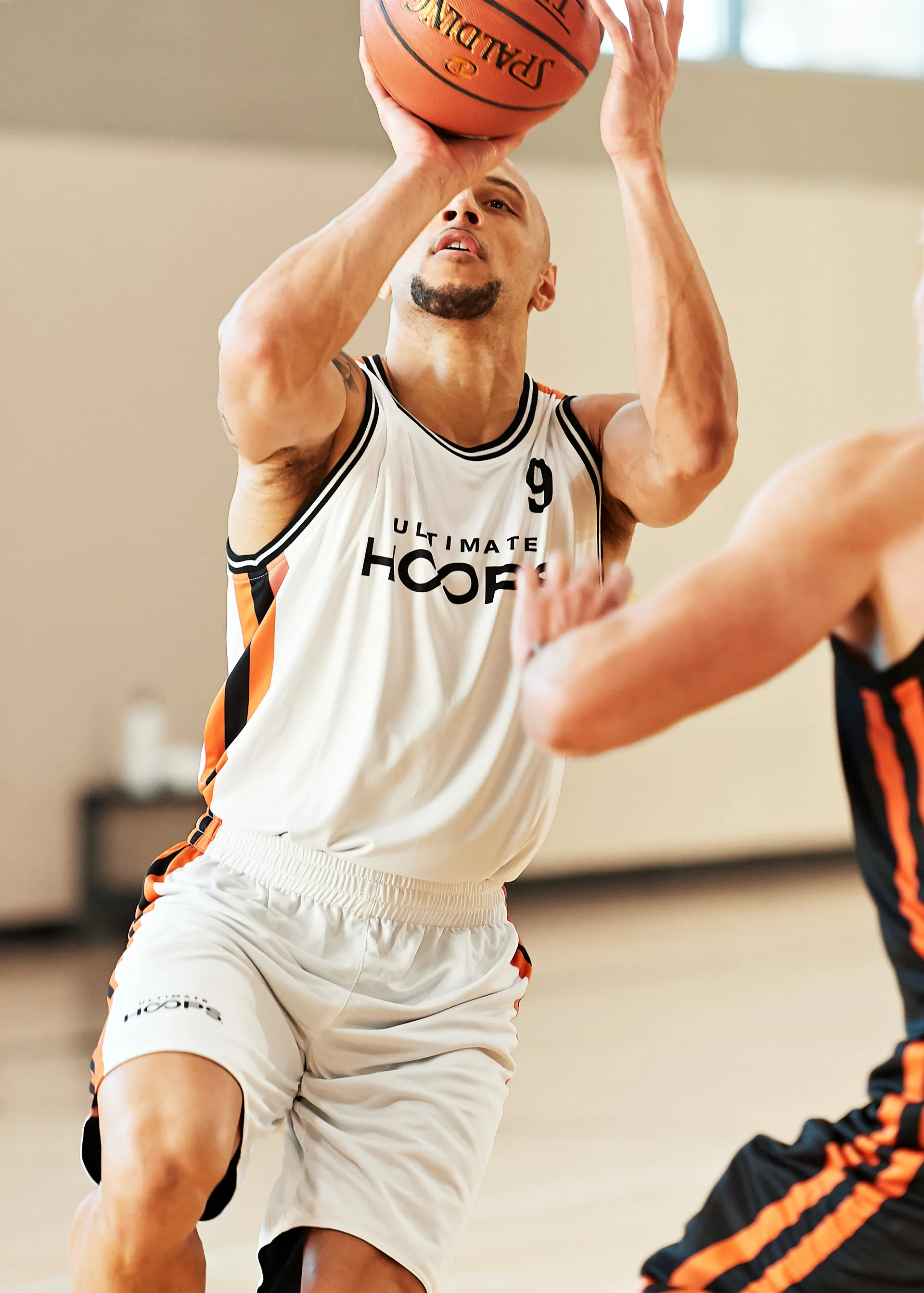 An adult basketball player dressed in tank and shorts shooting a basketball.