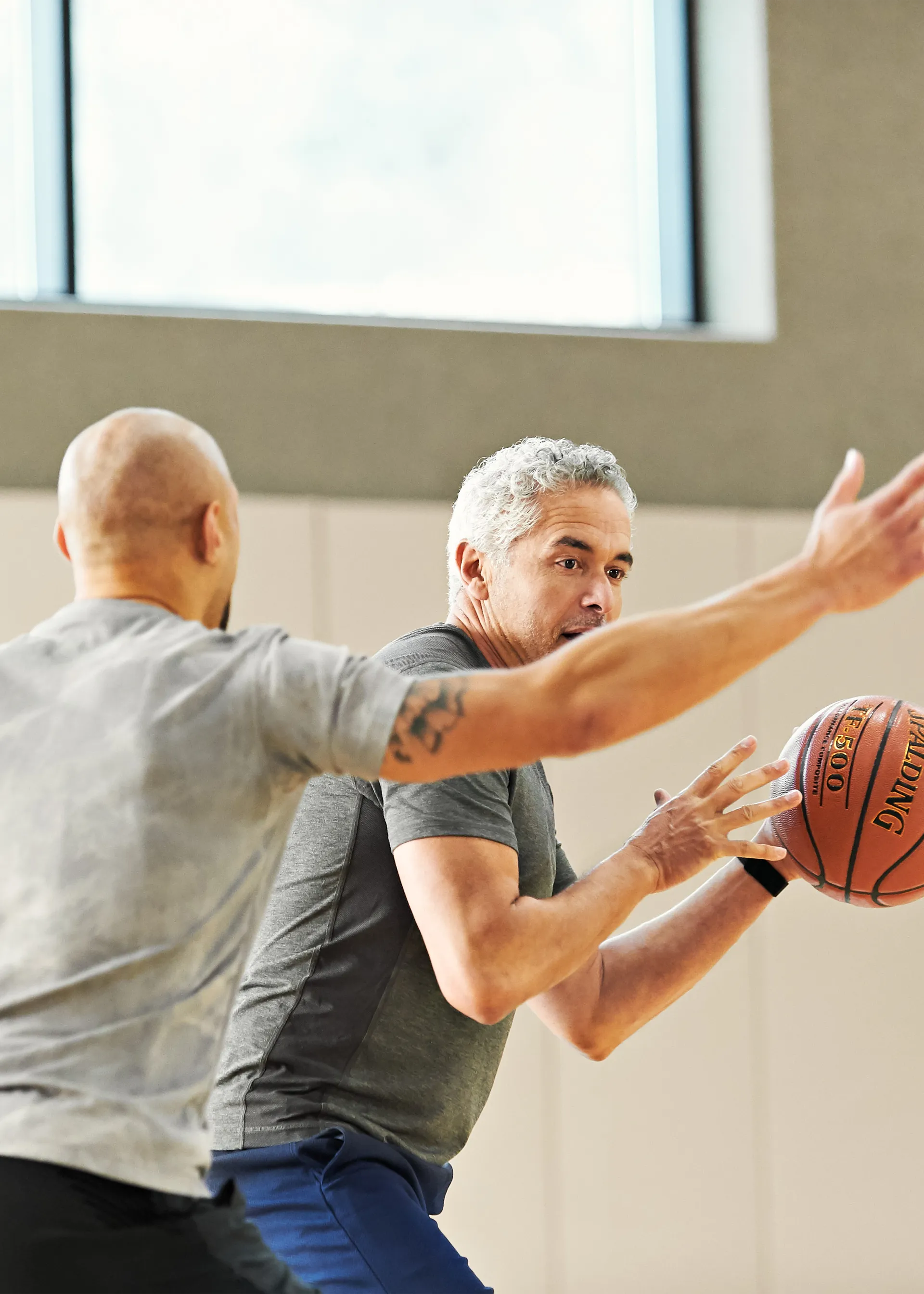 Two men playing basketball on an indoor court.