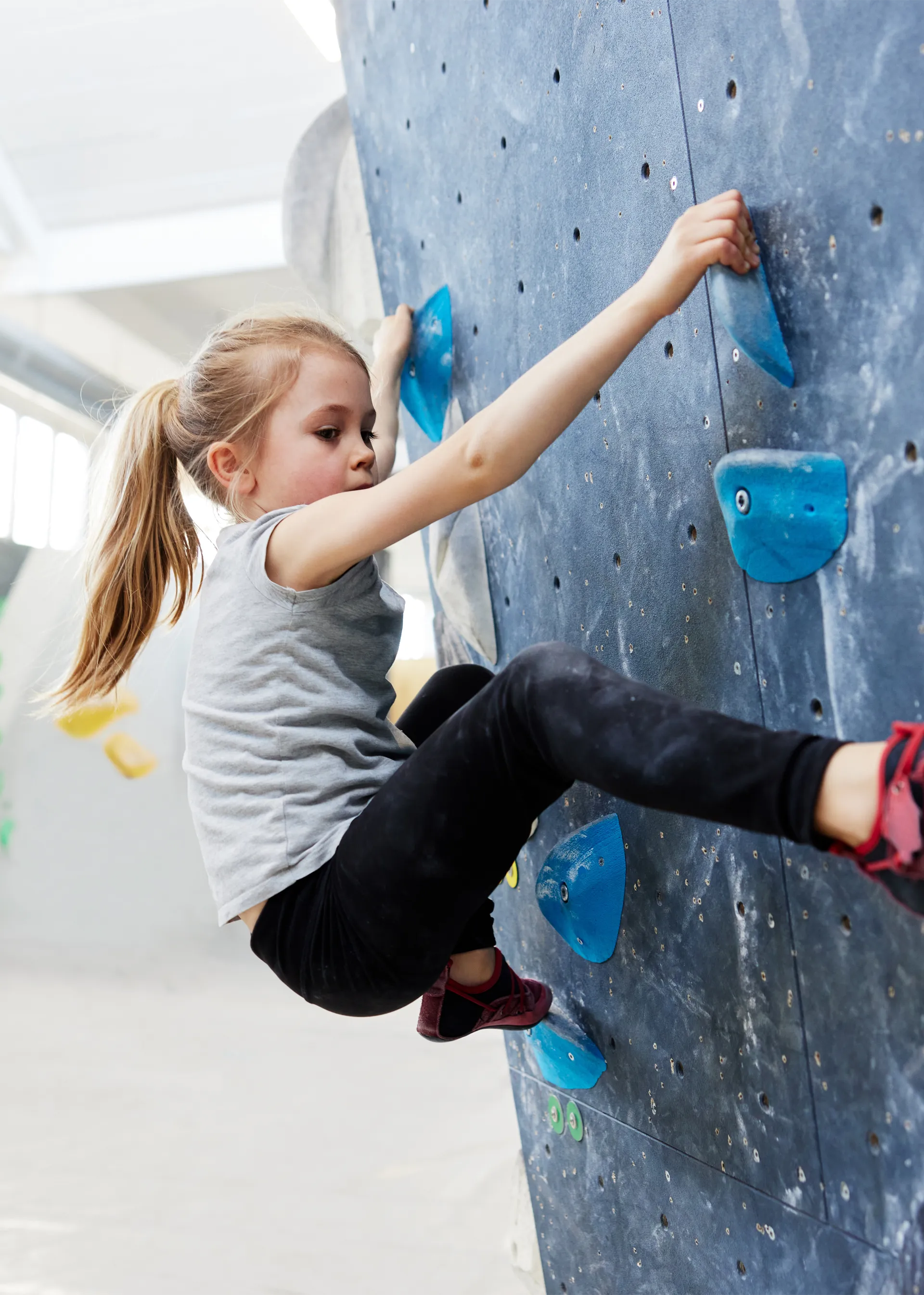 A close-up of a child climbing on an indoor rock wall.