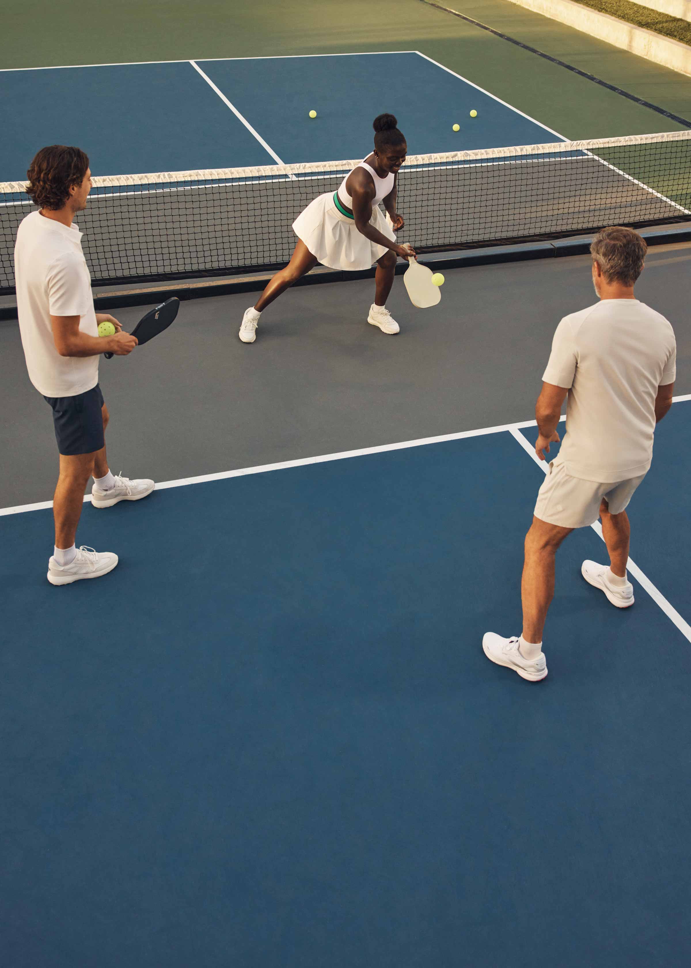 Three pickleball players working on their technique on a Life Time court