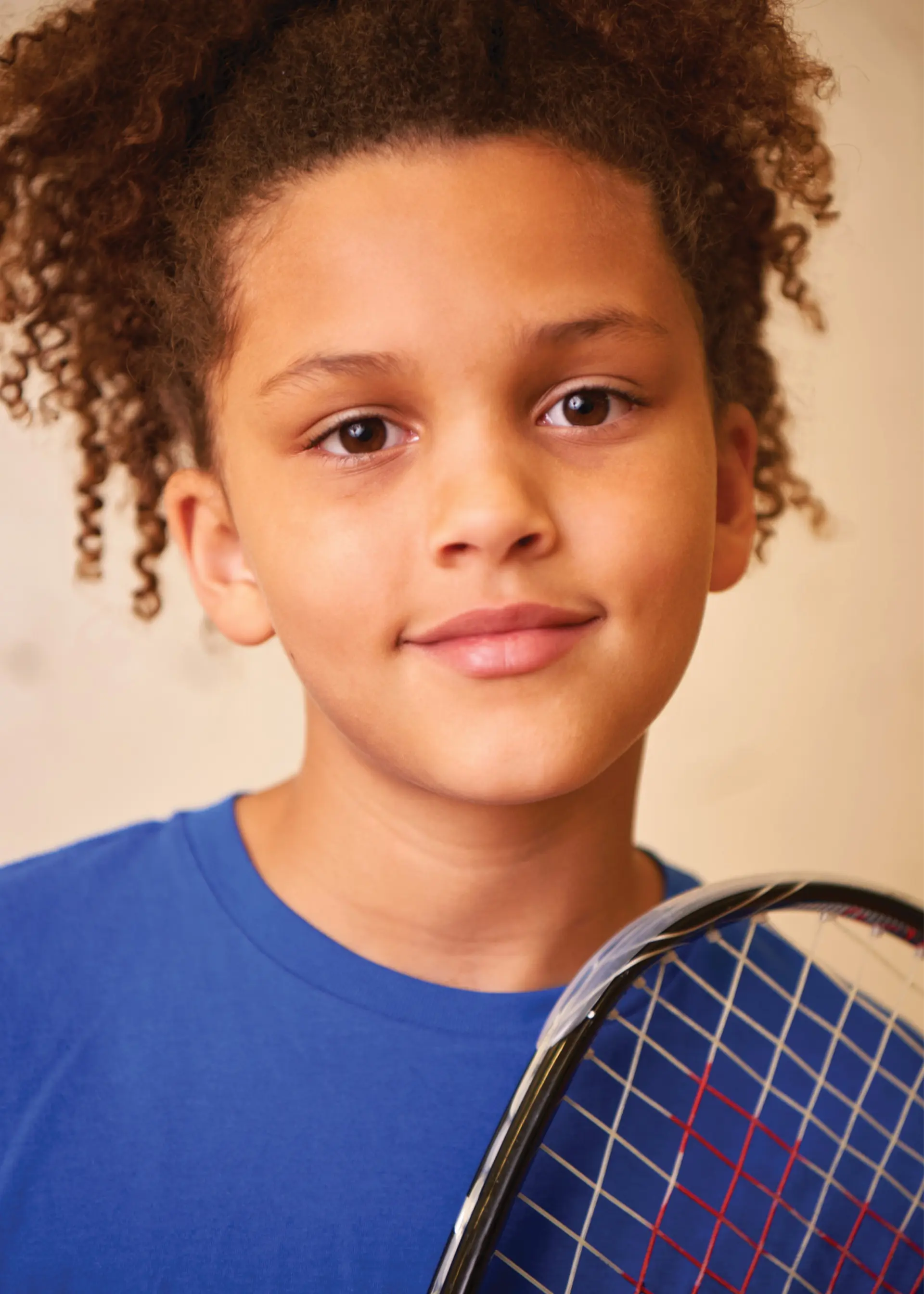 A close up of a child holding a racquet.