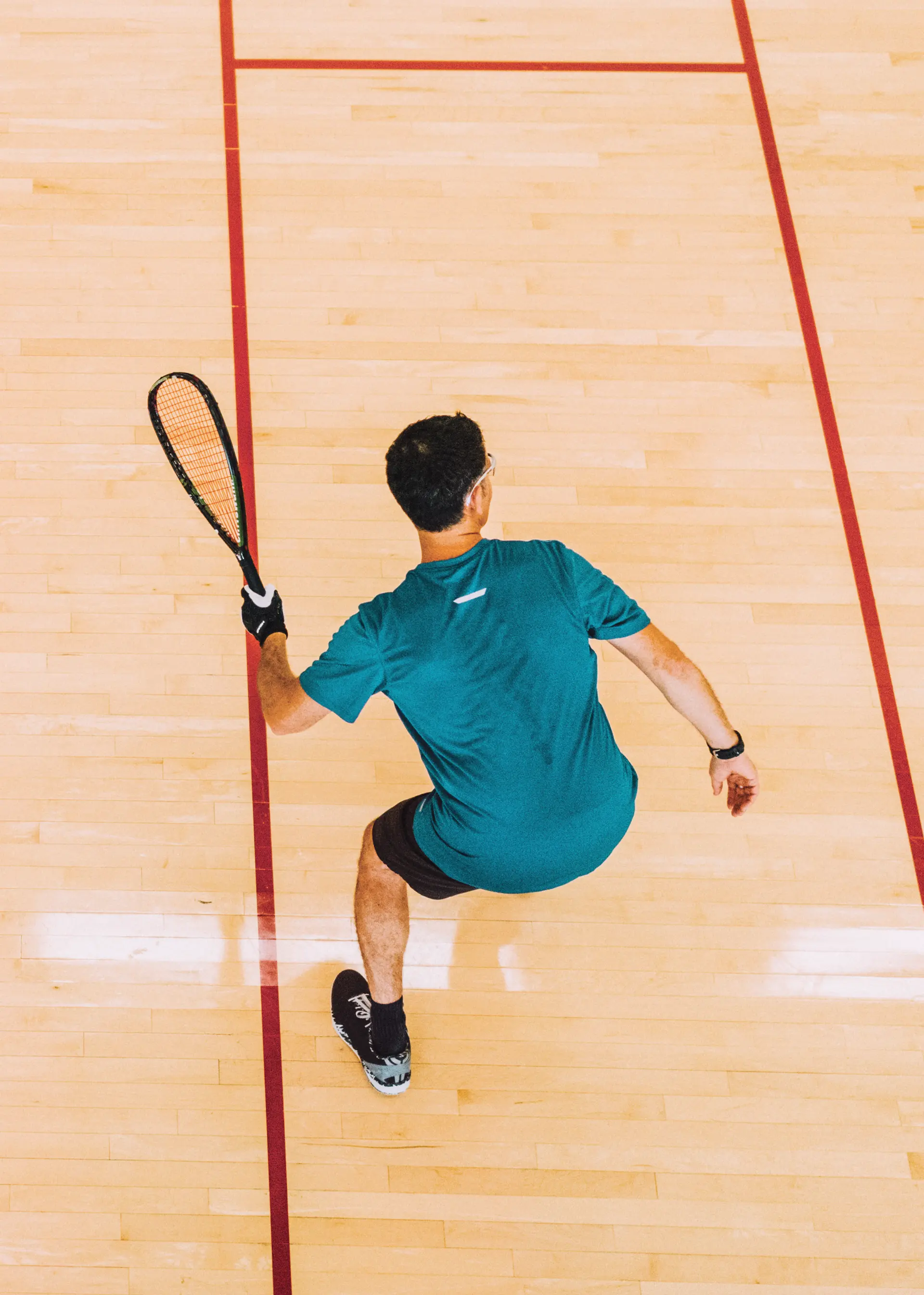 Aerial view of a person holding a racquet on an indoor court.