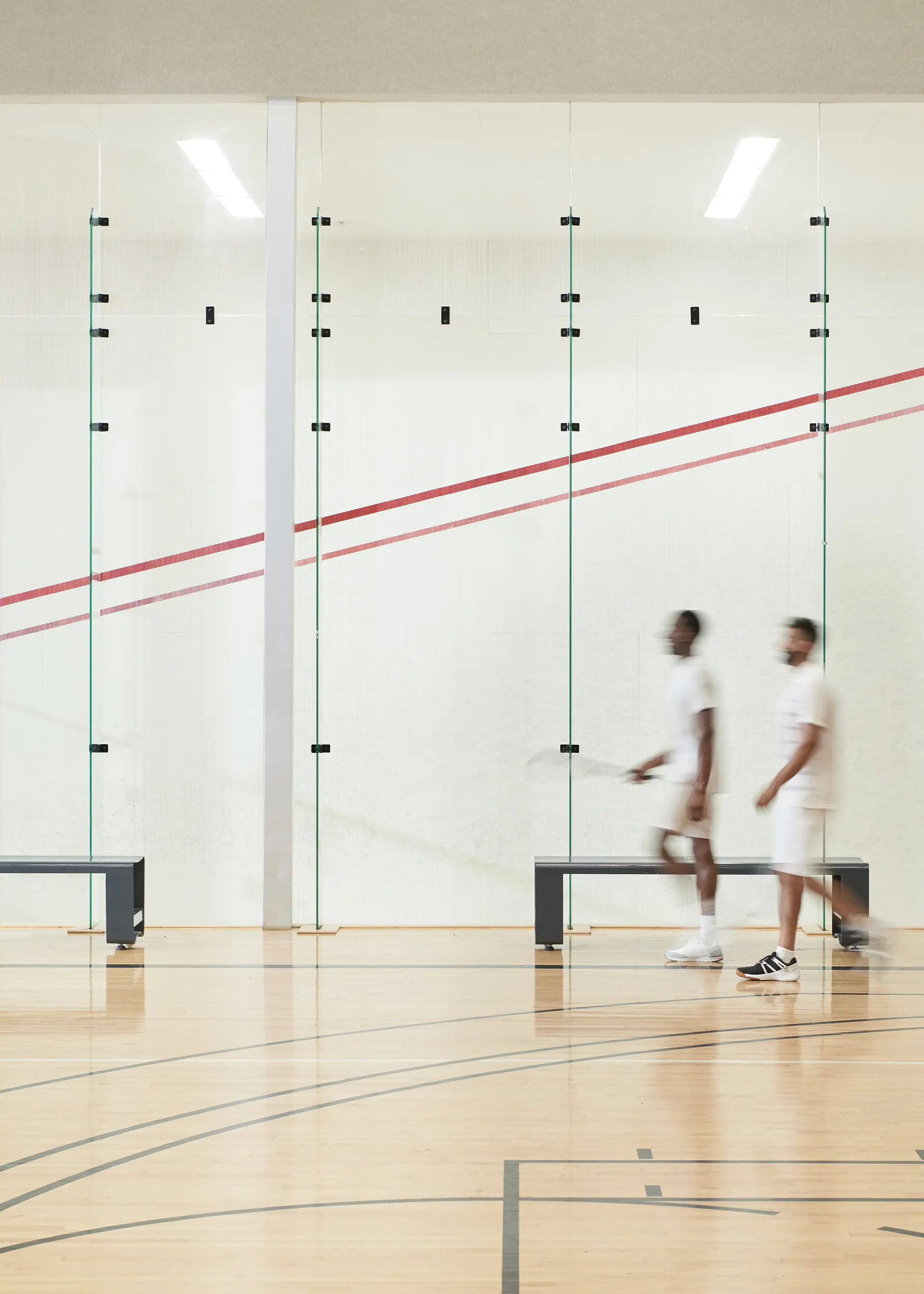 Two blurred or stylized people walking on an indoor court.