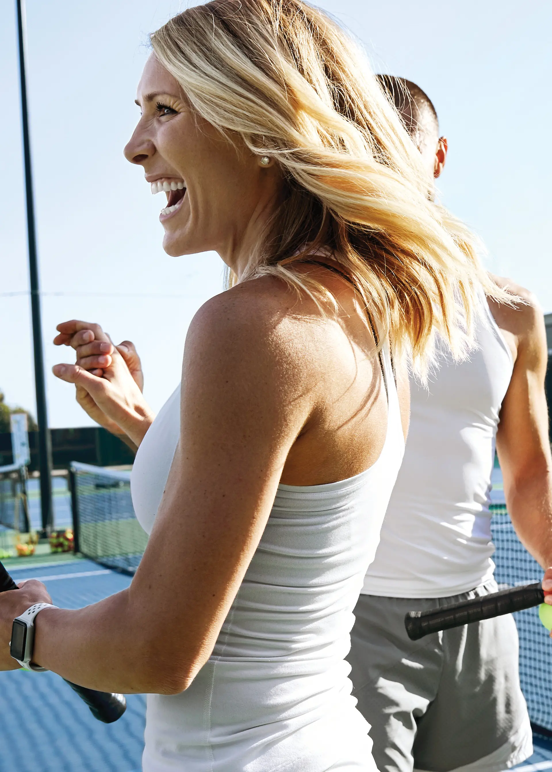Person smiling and high-fiving another person on an outdoor tennis court