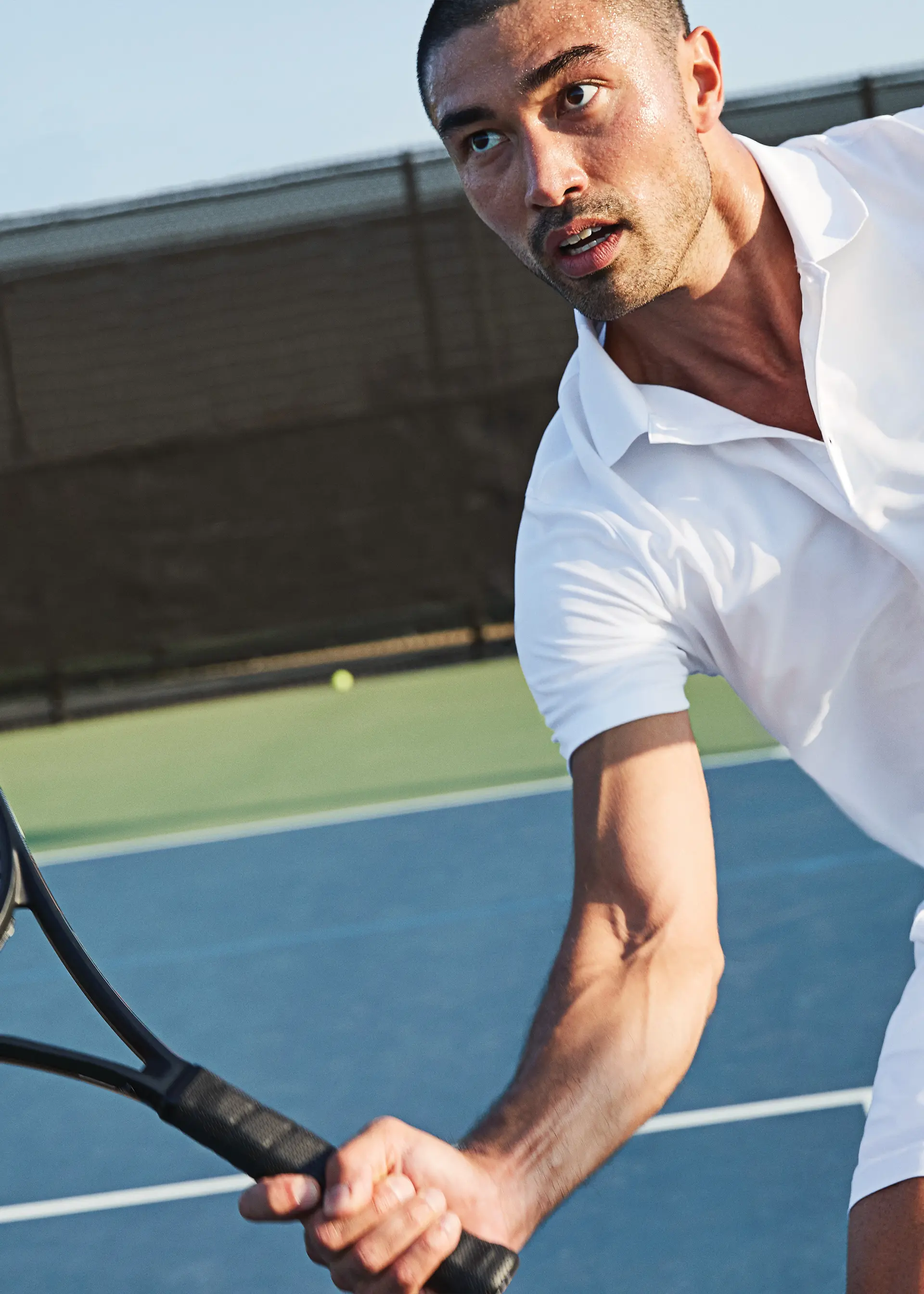 A man wearing a white tennis shirt and holding a tennis racket.
