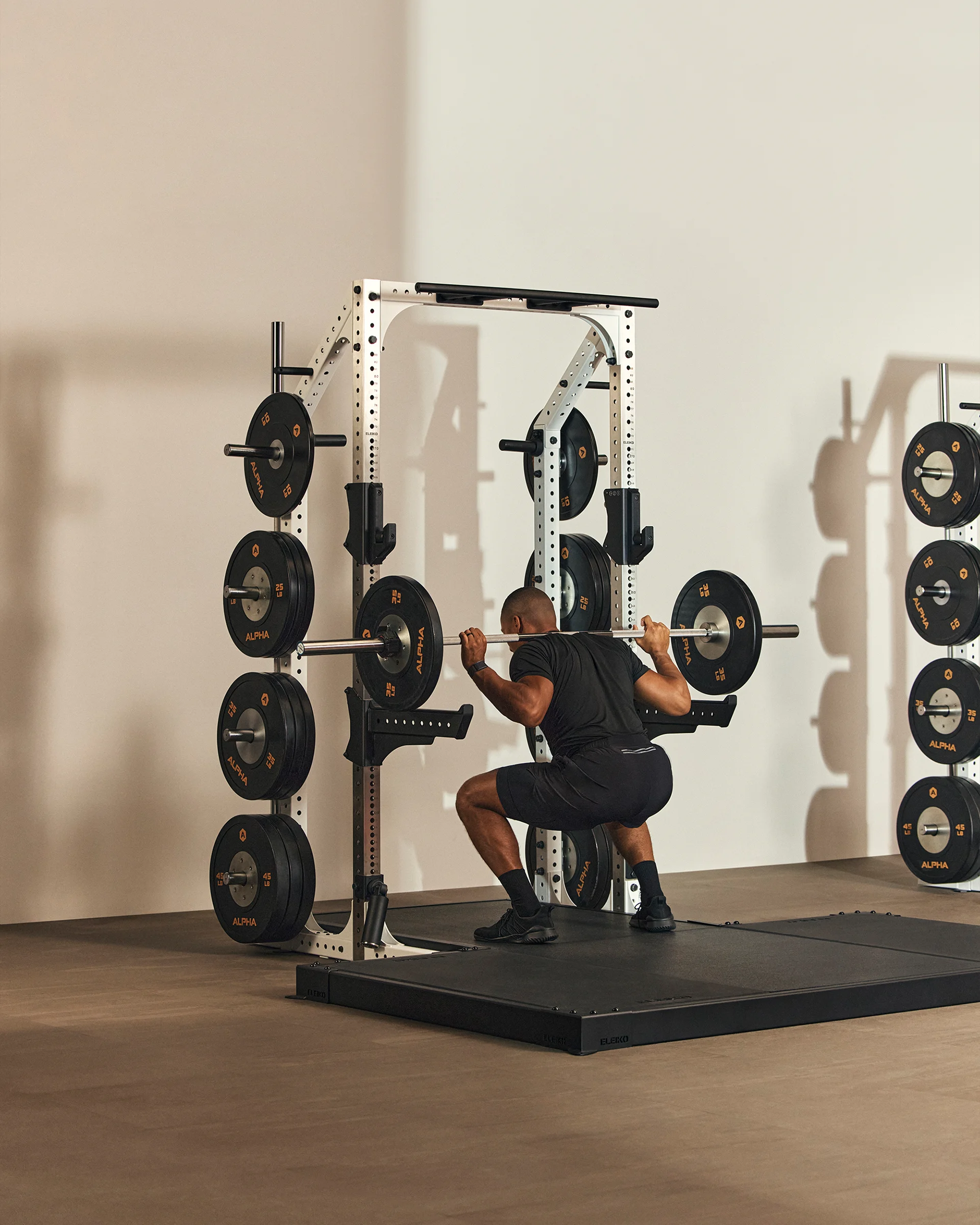 A Life Time member doing a barbell back squat.