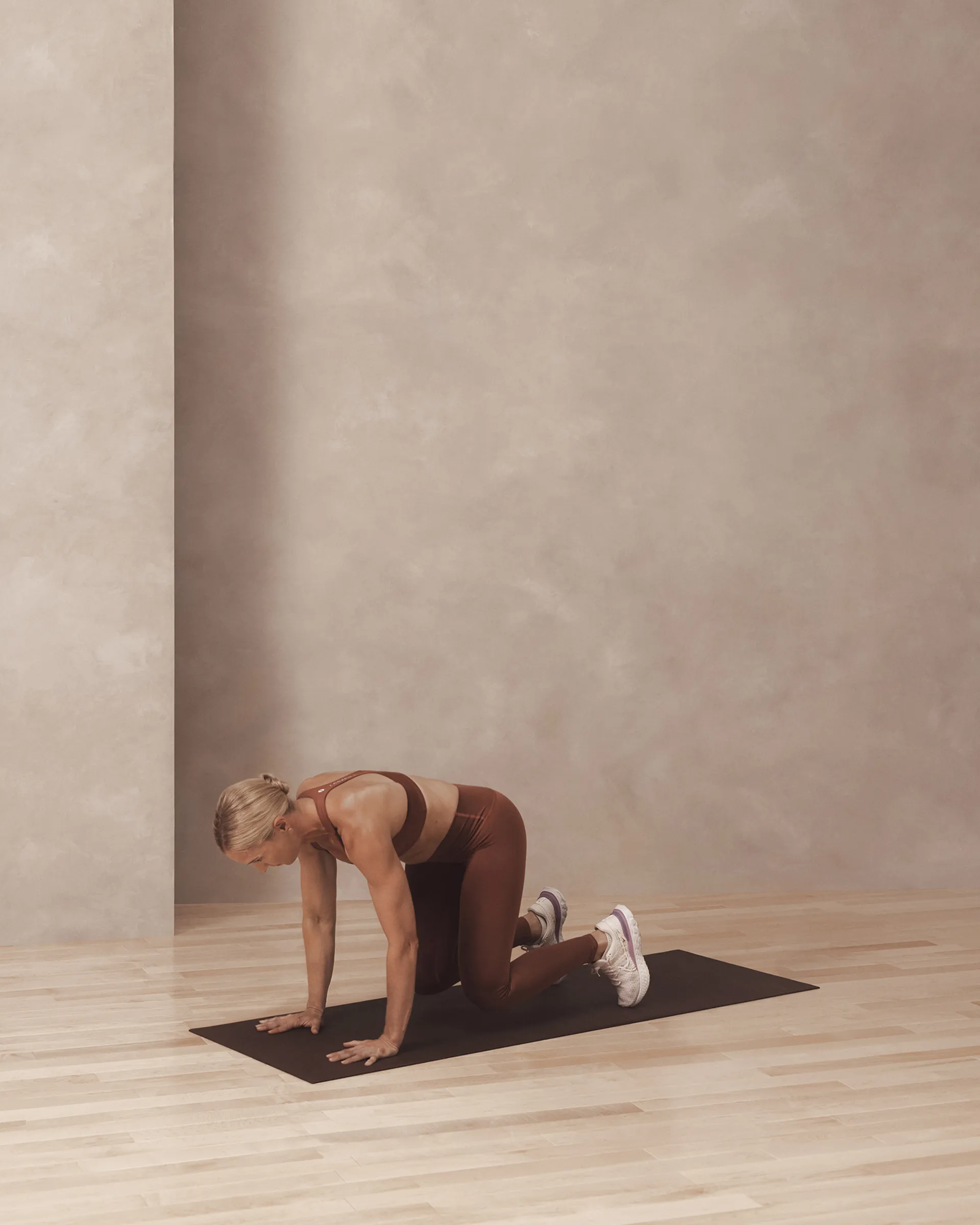 A Life Time member in a bear pose on a yoga mat.