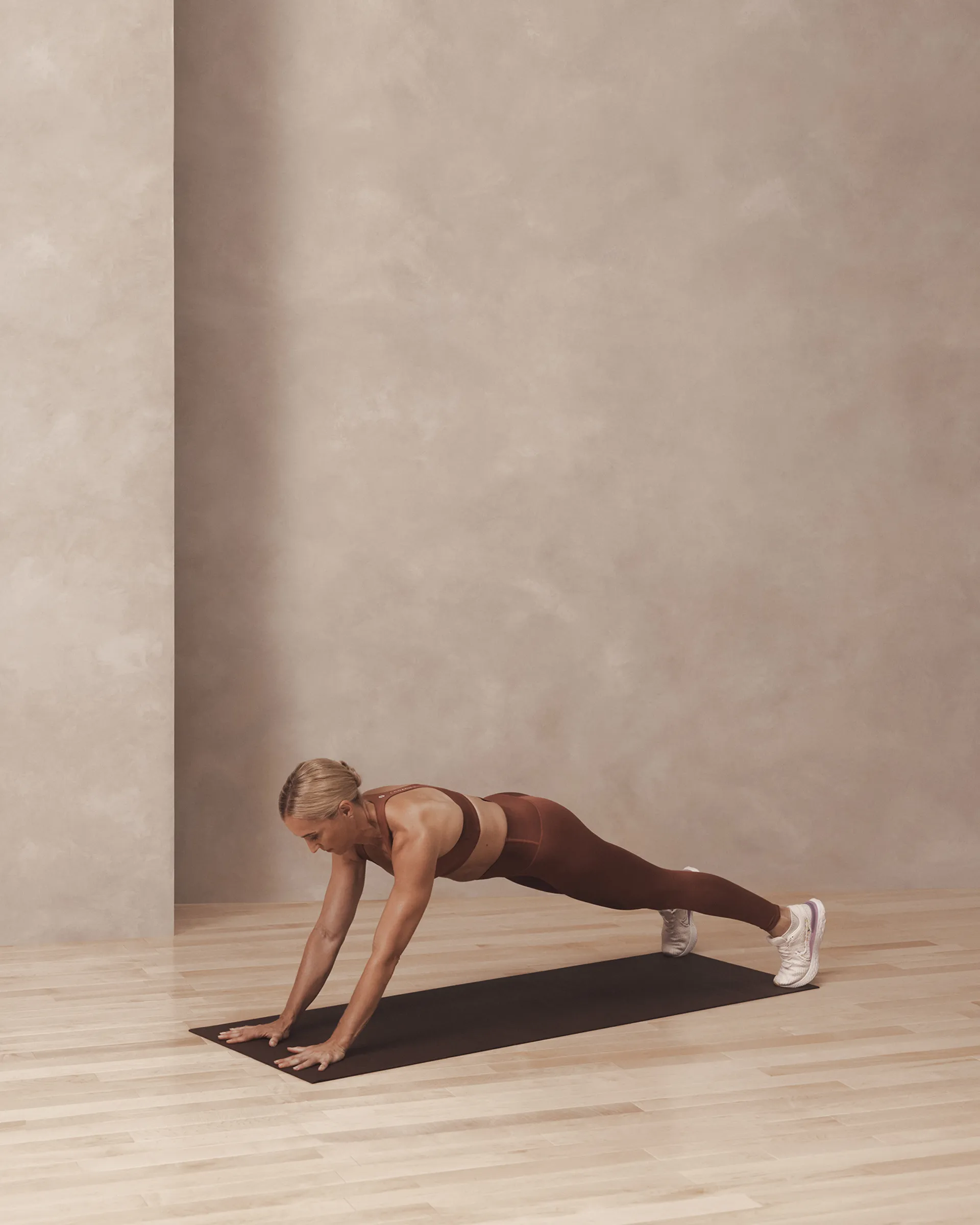 A Life Time member holding a brooklyn plank on a yoga mat.