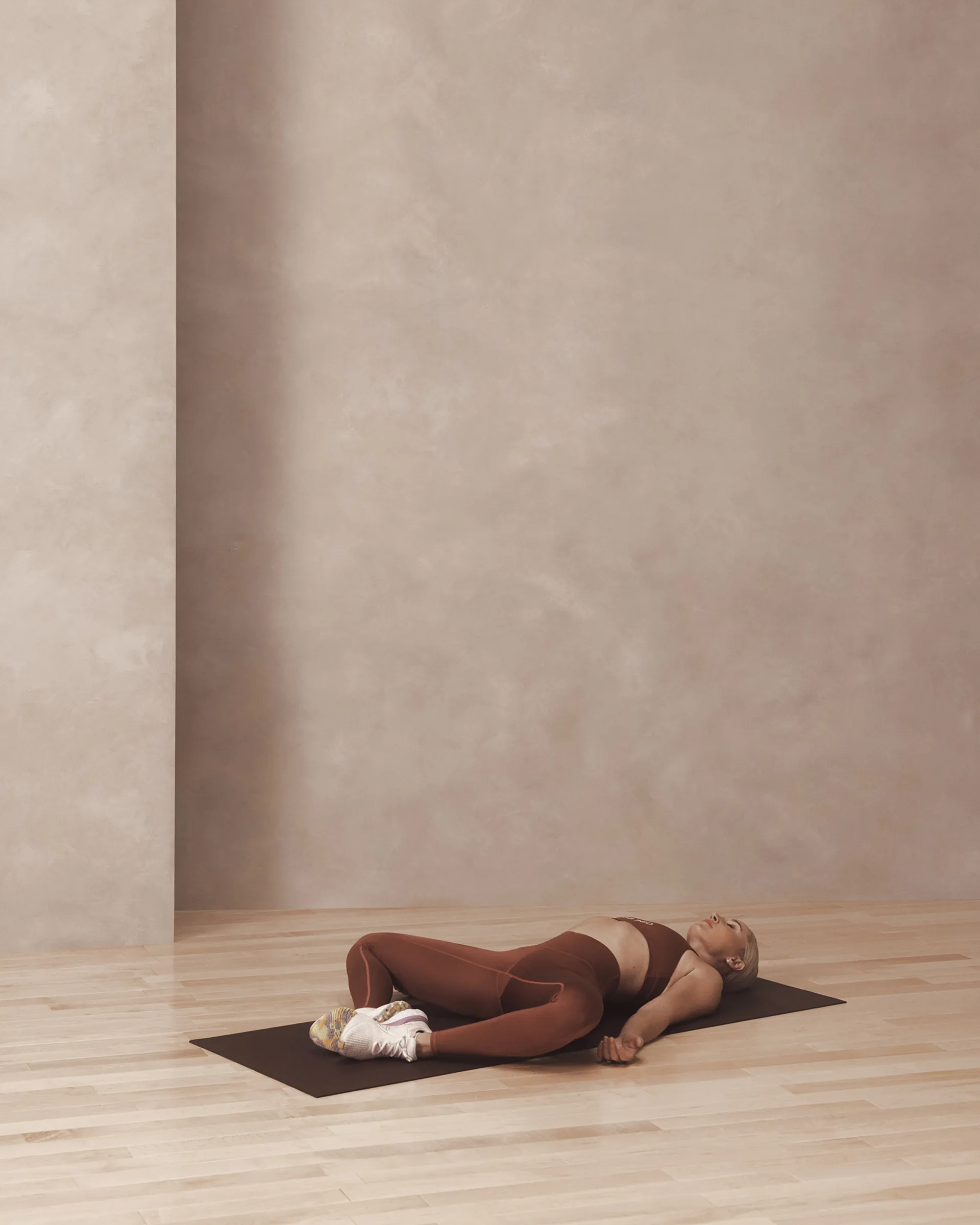 A Life Time member in a supine butterfly pose on a yoga mat.