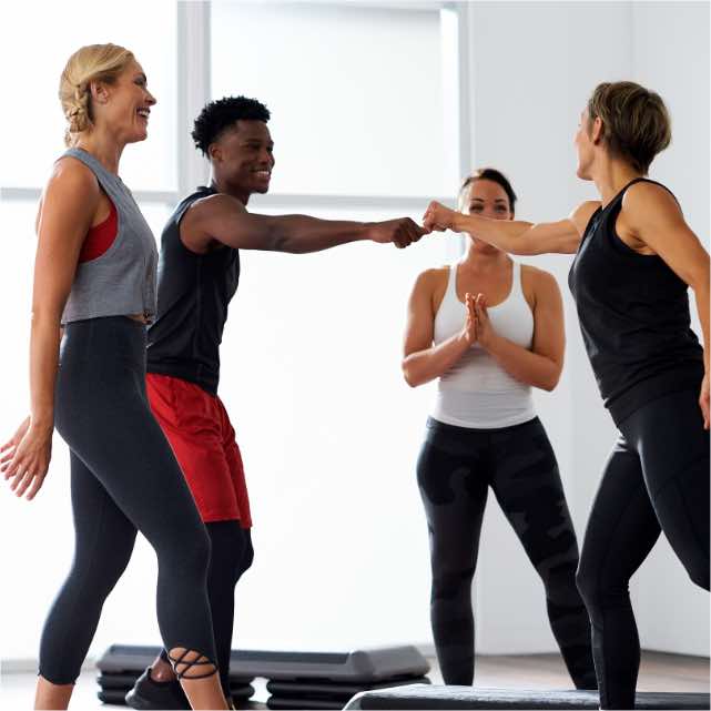 A group of people fist bumping and celebrating during a small group training class at Life Time.