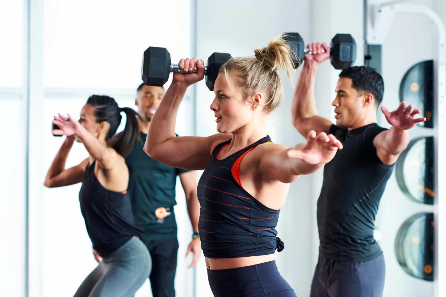 Three people holding dumbbells in a group training class at Life Time