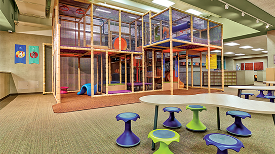 The kids academy with tables and chairs for kids and a large indoor play maze