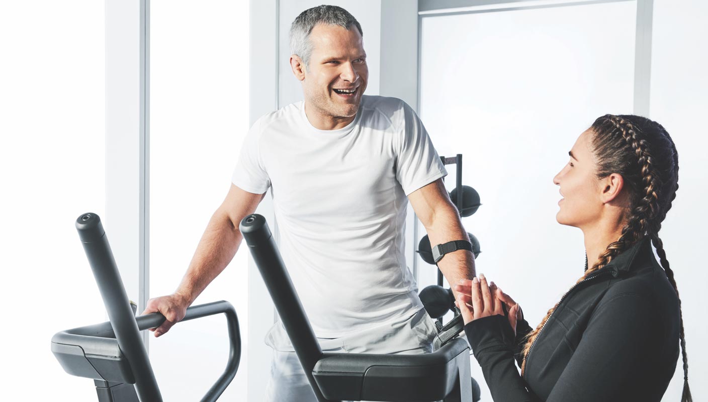 a man talks to a trainer while exercising