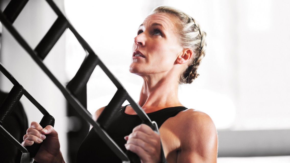 Woman doing a modified pullup with trx bands. 