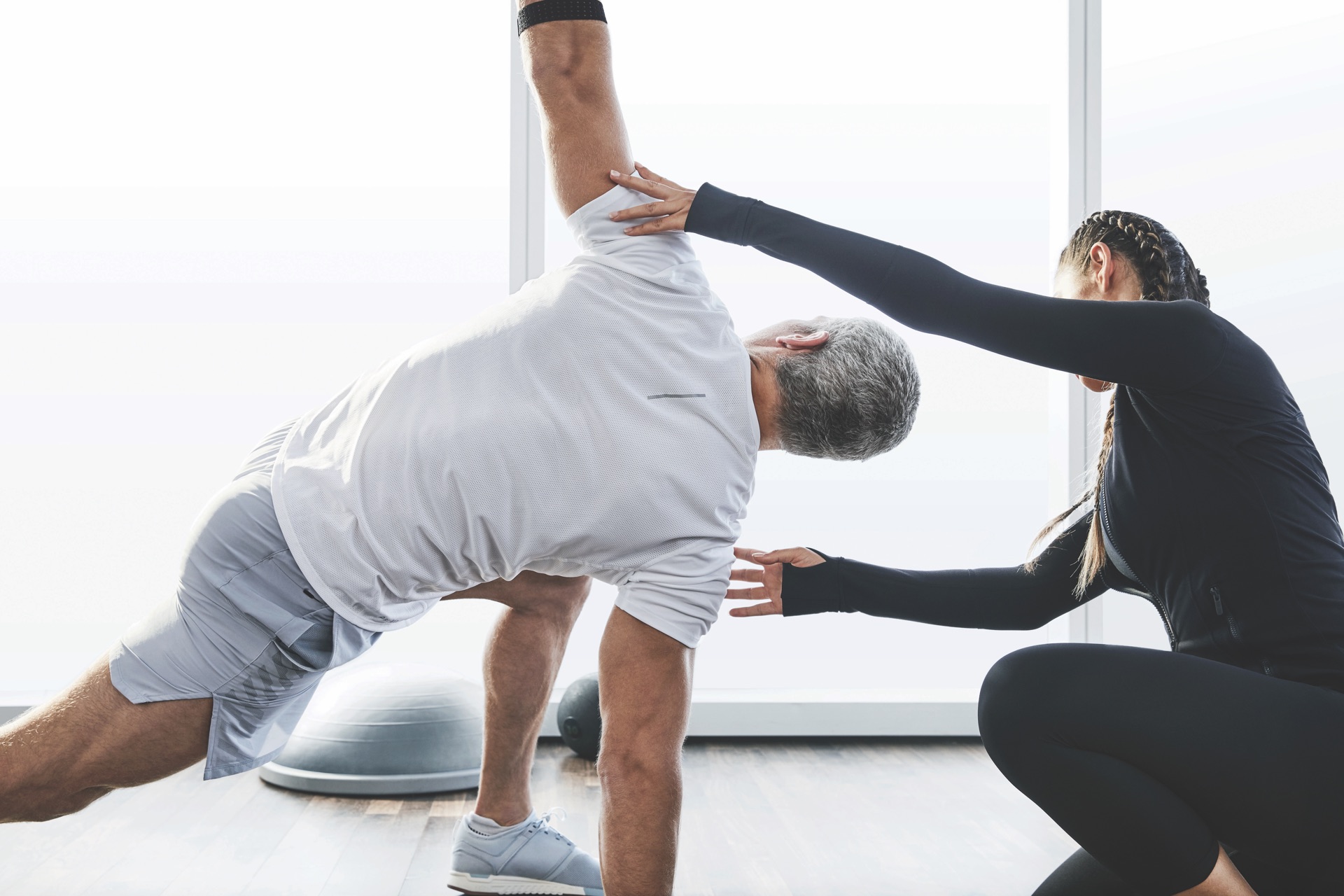Woman personal trainer helping a man stretch at Life Time