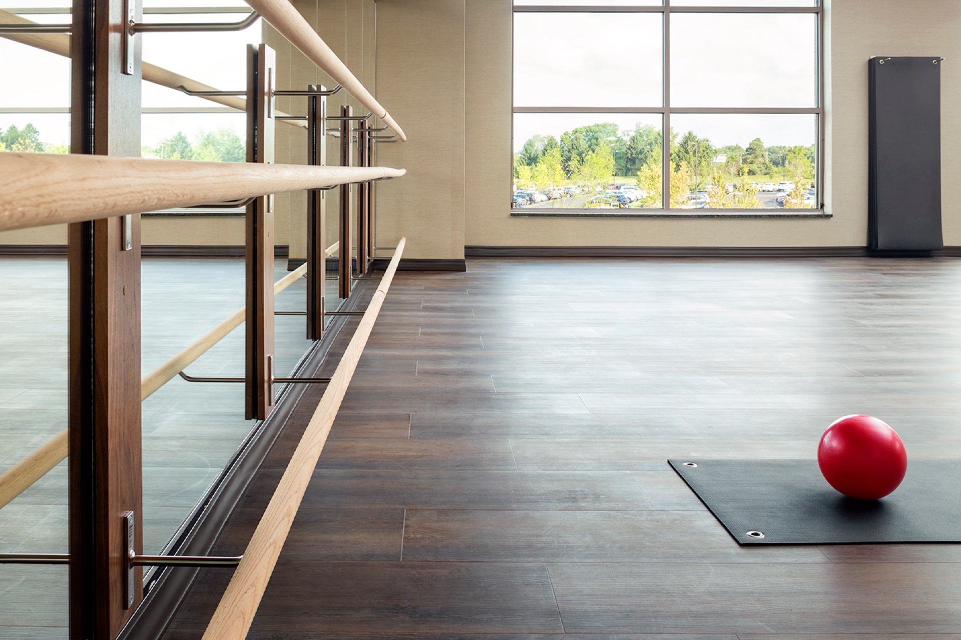 Yoga mat and red Pilates ball on the floor of a group fitness studio