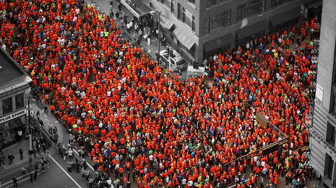 An aerial view of a Life Time race, with over a hundred participants in red shirts in a downtown area