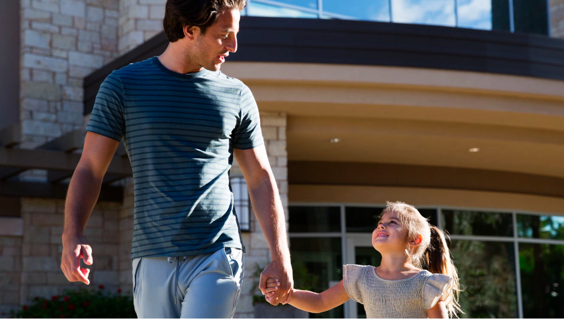 a dad walking and holding hands with his daughter