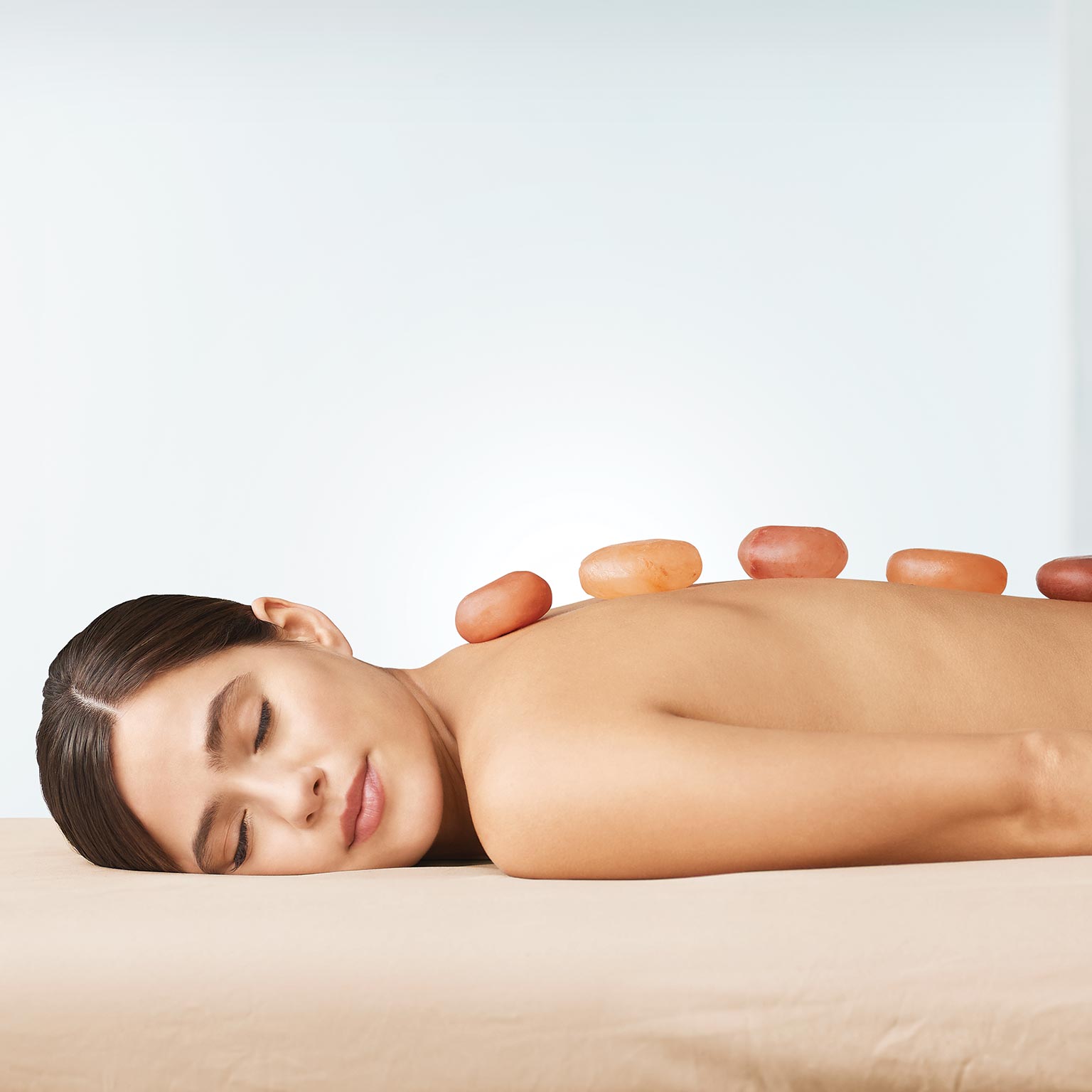 Image of a woman in a spa setting with stones on her back.