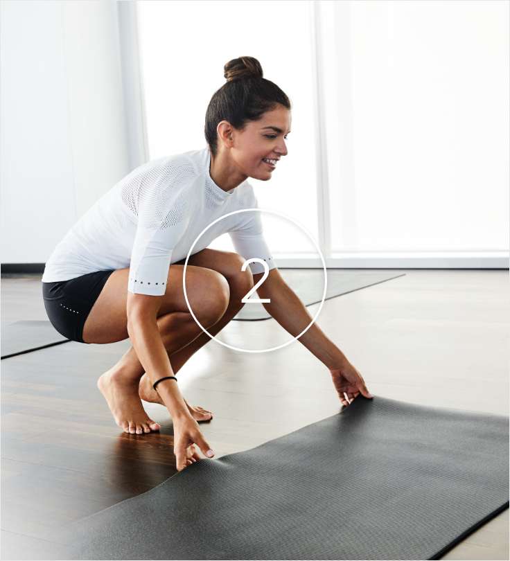 Woman laying out yoga mat in a studio. 