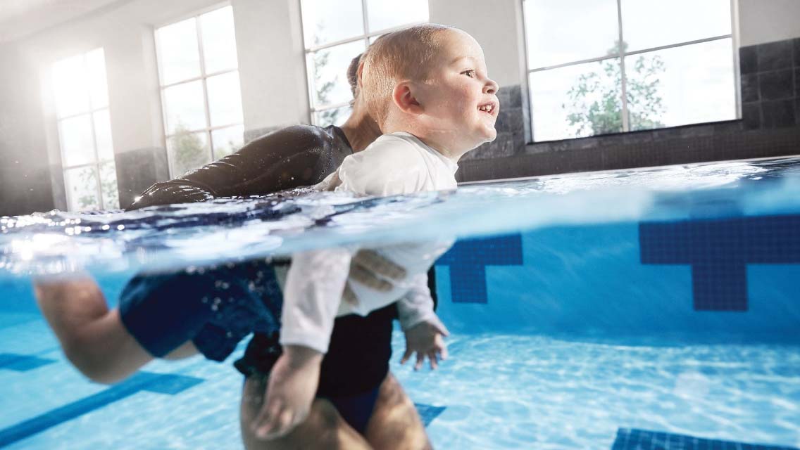 a child learning to swim with an instructor