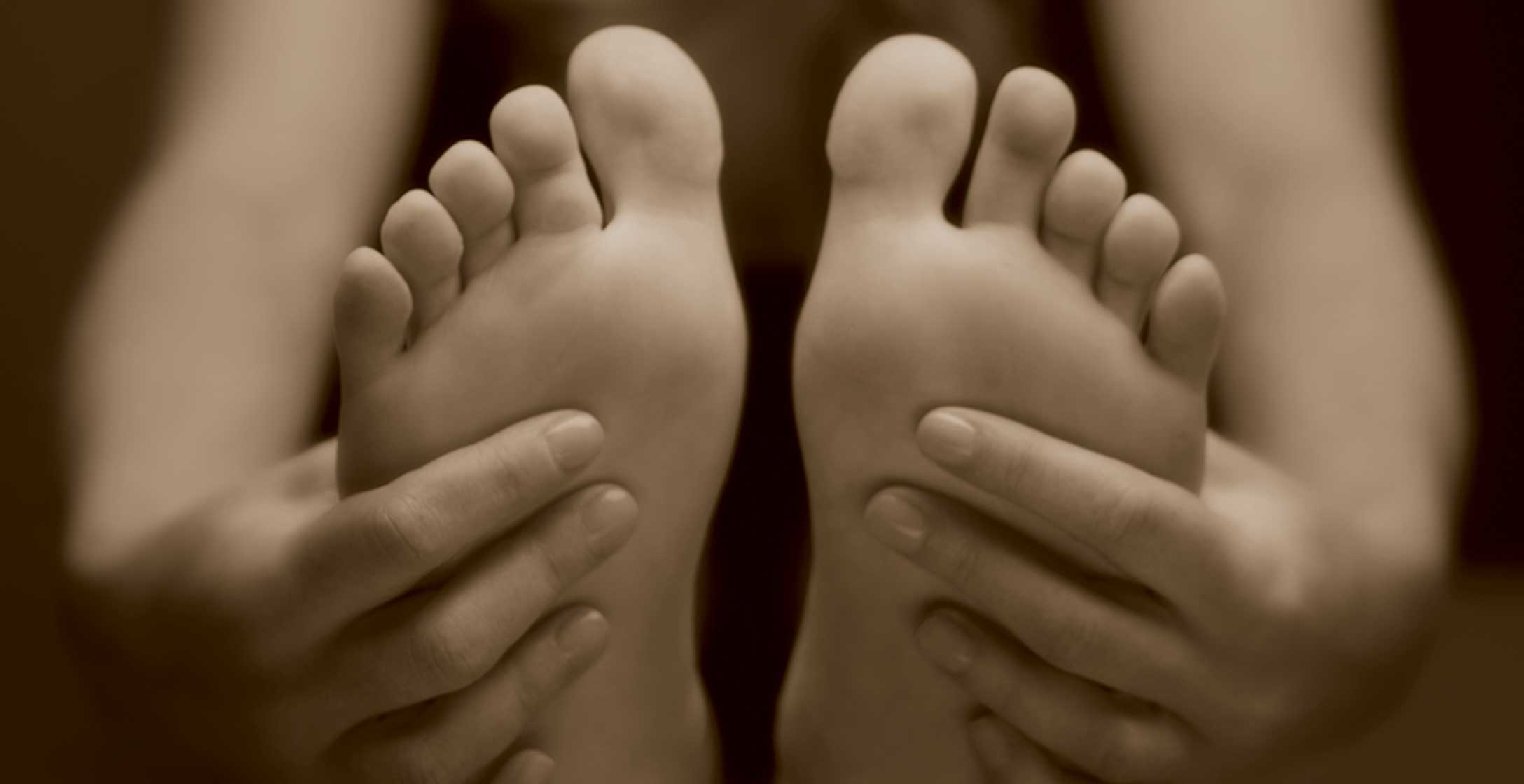 The hands and feet of a woman who is sitting and stretching forward
