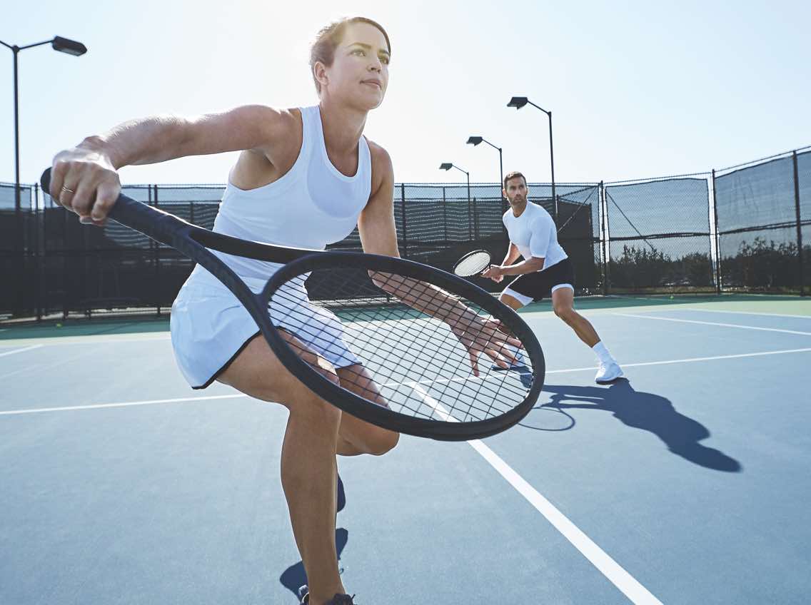 Man and woman playing tennis on an outdoor tennis court at Life Time