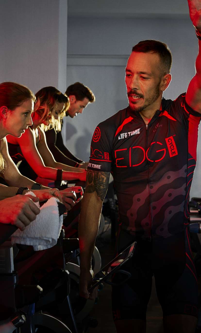 an instructor motivates an edge group indoor cycle class