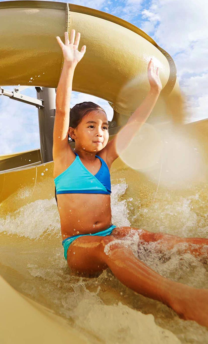 a girl goes down a waterslide with her hands in the air