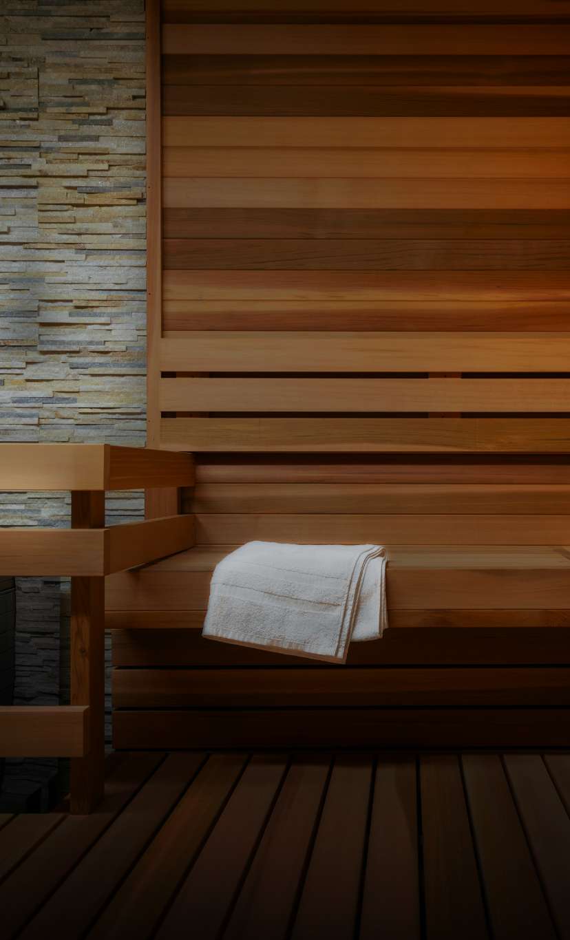 a folded white towel inside a cedar wood and stone sauna