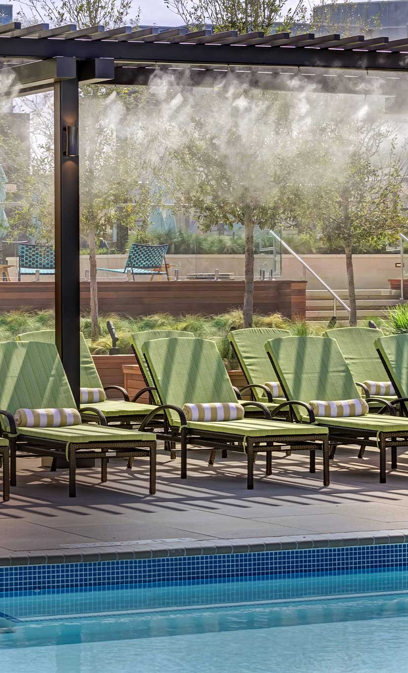 lounge chairs by an outdoor pool with outdoor misters overhead