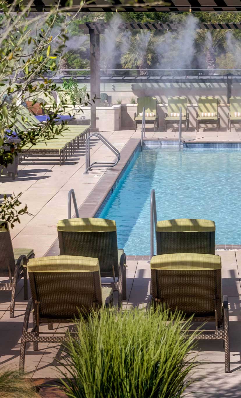 lounge chairs and lush greenery on an outdoor pool deck