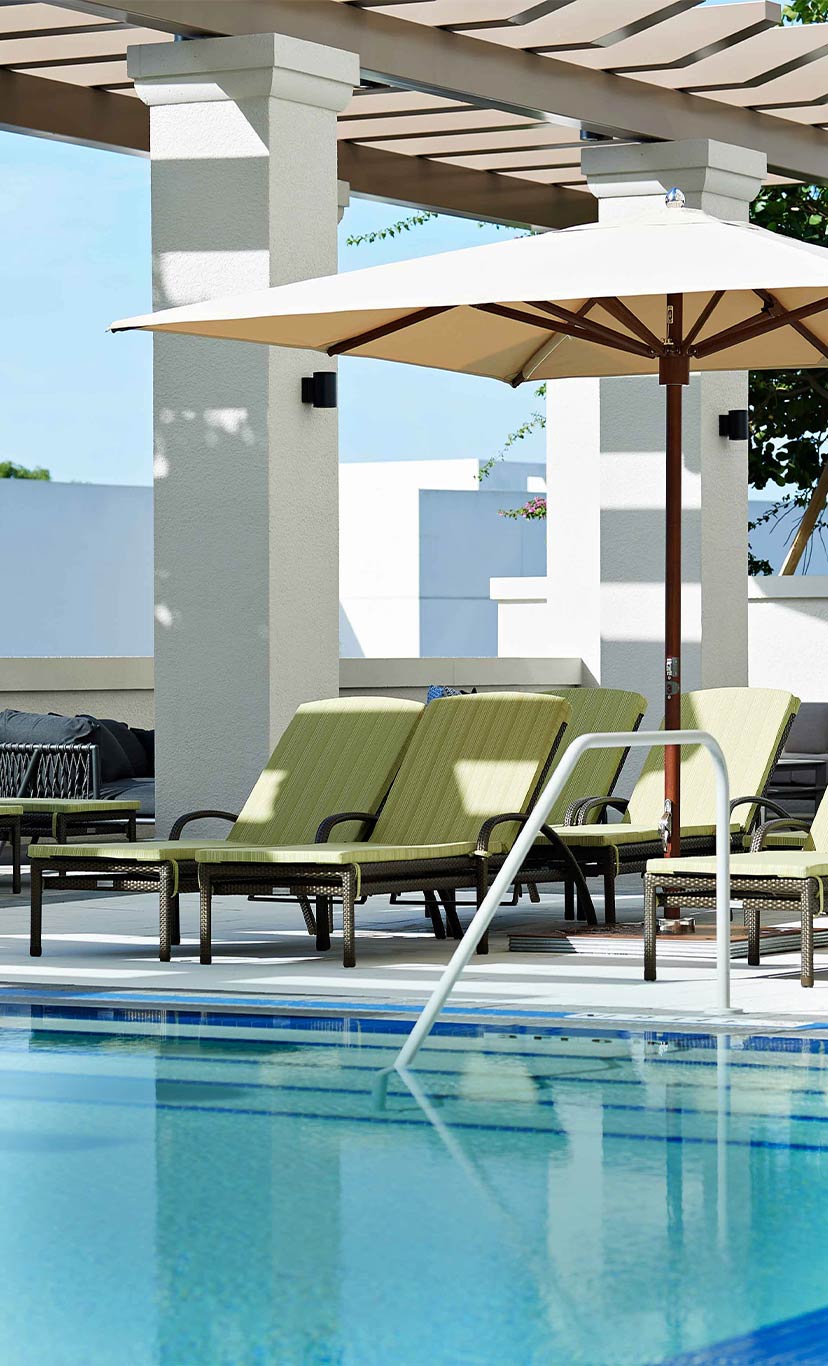 lounge chairs sit at the edge of an outdoor leisure pool