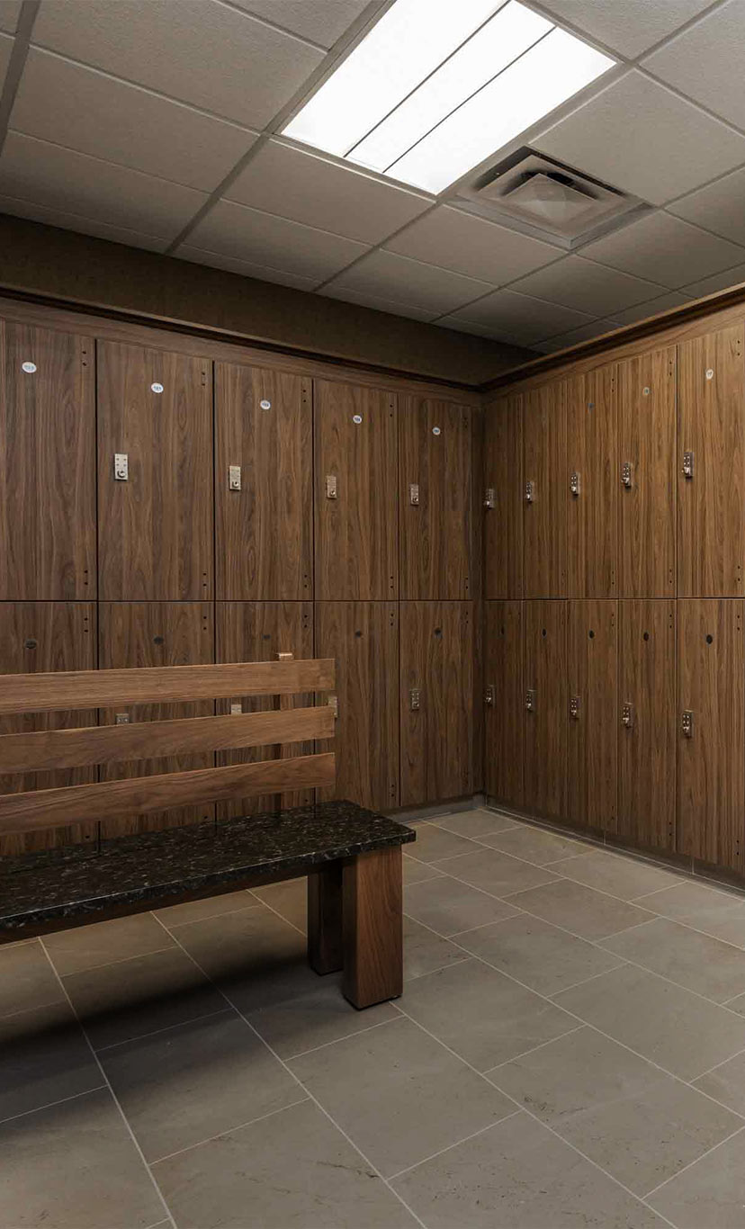 floor to ceiling wood lockers and marble floor and benches in a luxury locker room