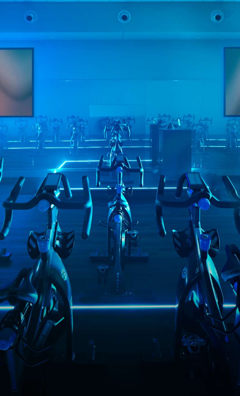 a blue lit indoor cycle studio
