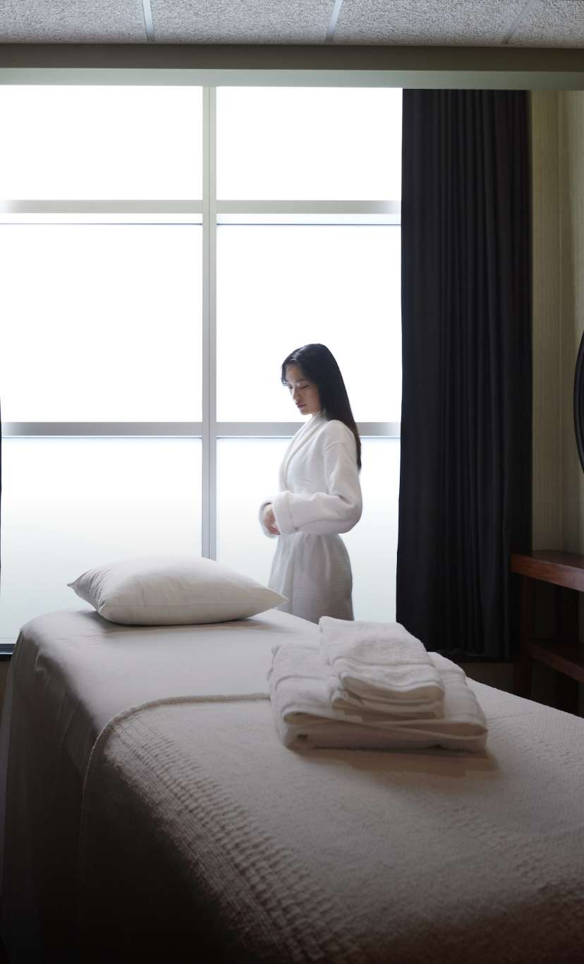 a woman in a robe stands by a massage table