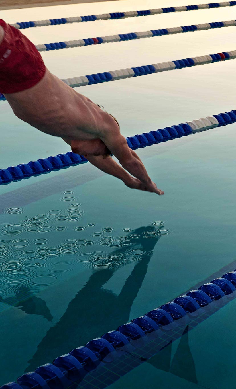 a man dives into an outdoor lap pool lane