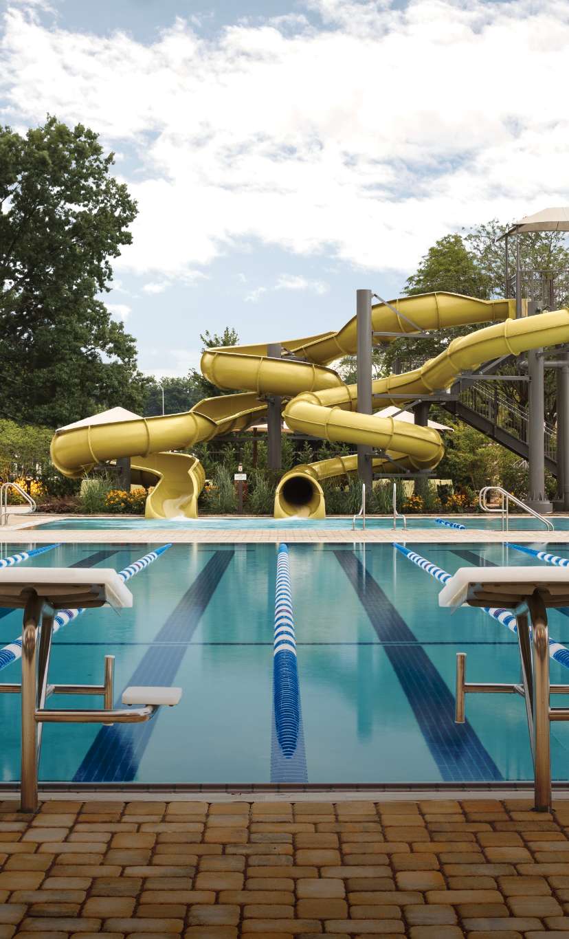 2 waterslides that empty into an outdoor pool behine a 6 lane lap pool