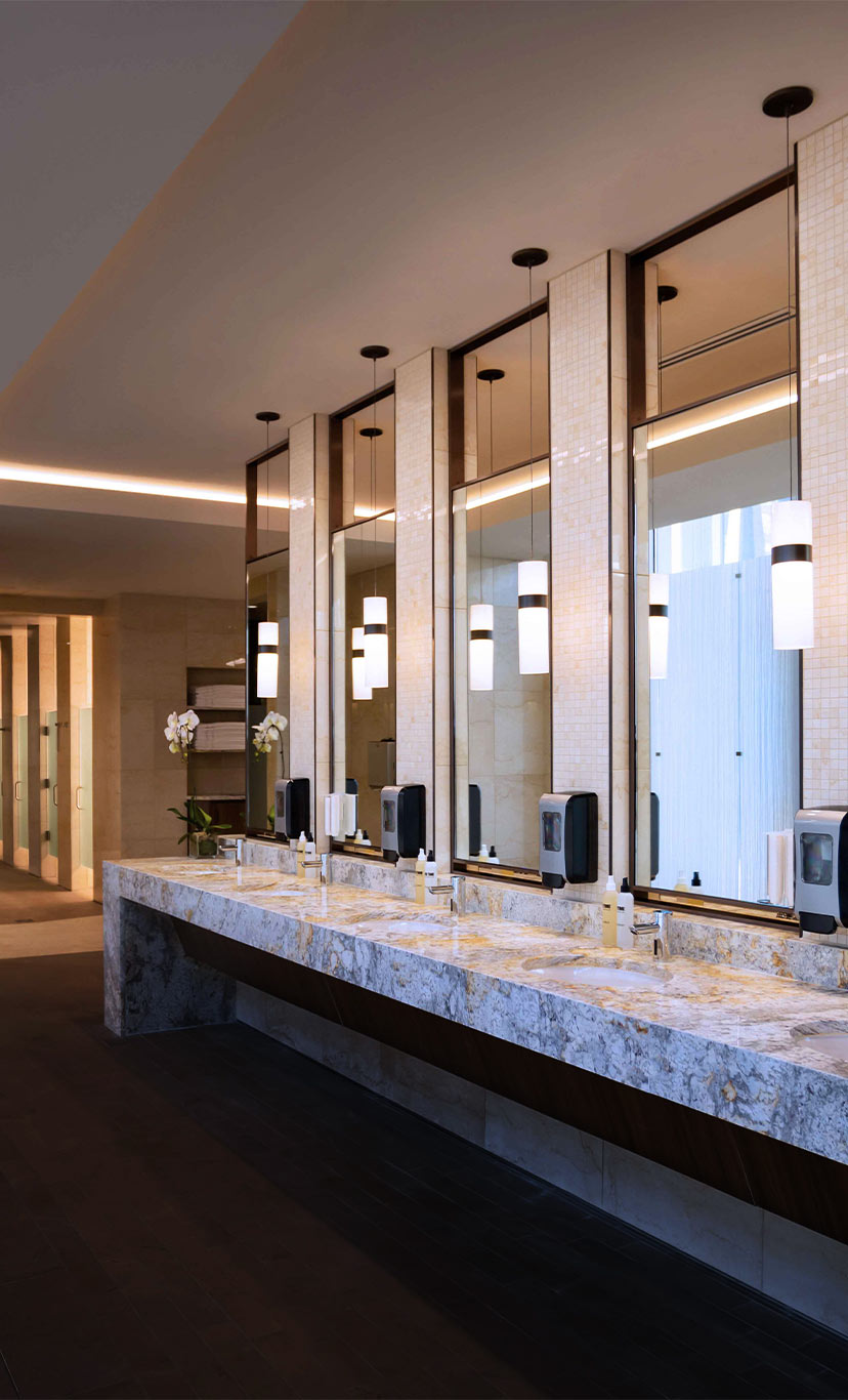 an expansive luxury locker room with marble sinks and vanity area