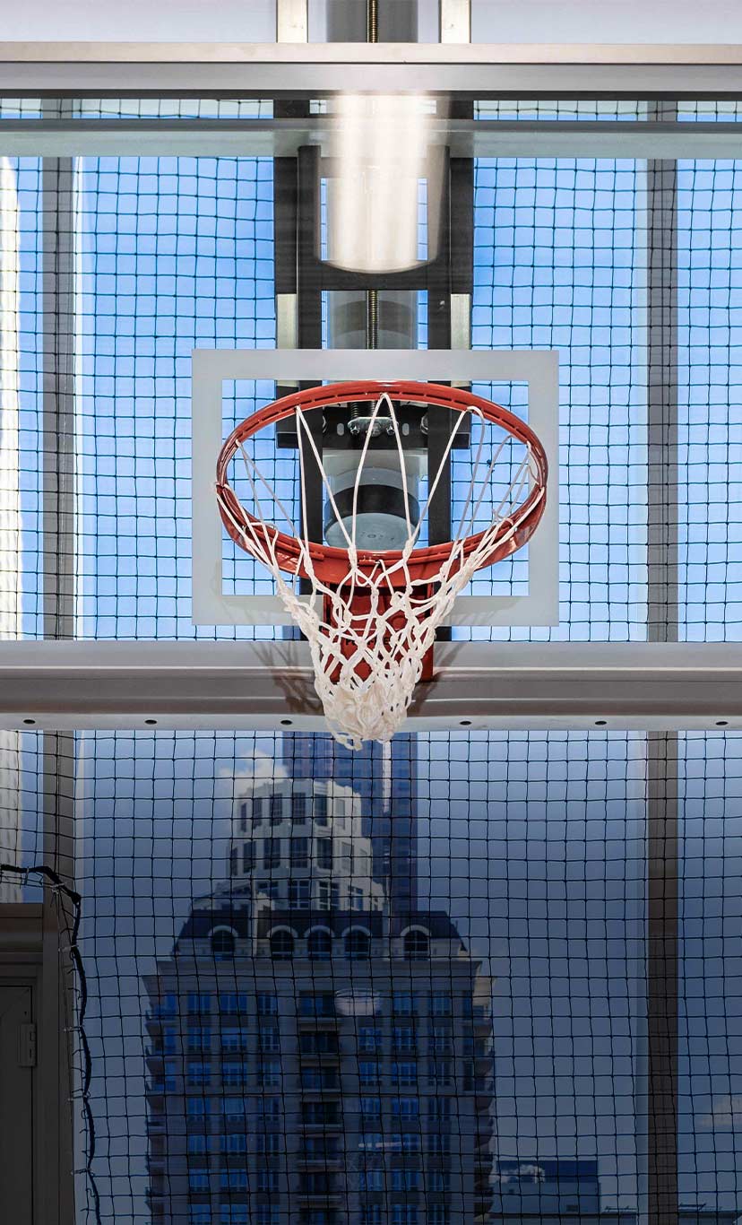a basketball hoop with large windows and a city skyline in the background