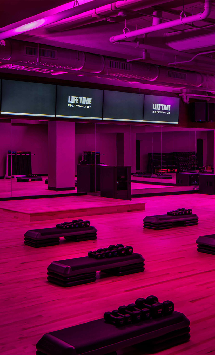 aerobic steps and dumbells in a pink lit studio workout space