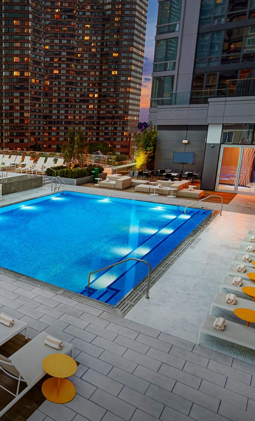 An outdoor rooftop pool oasis surrounded by skyscrappers