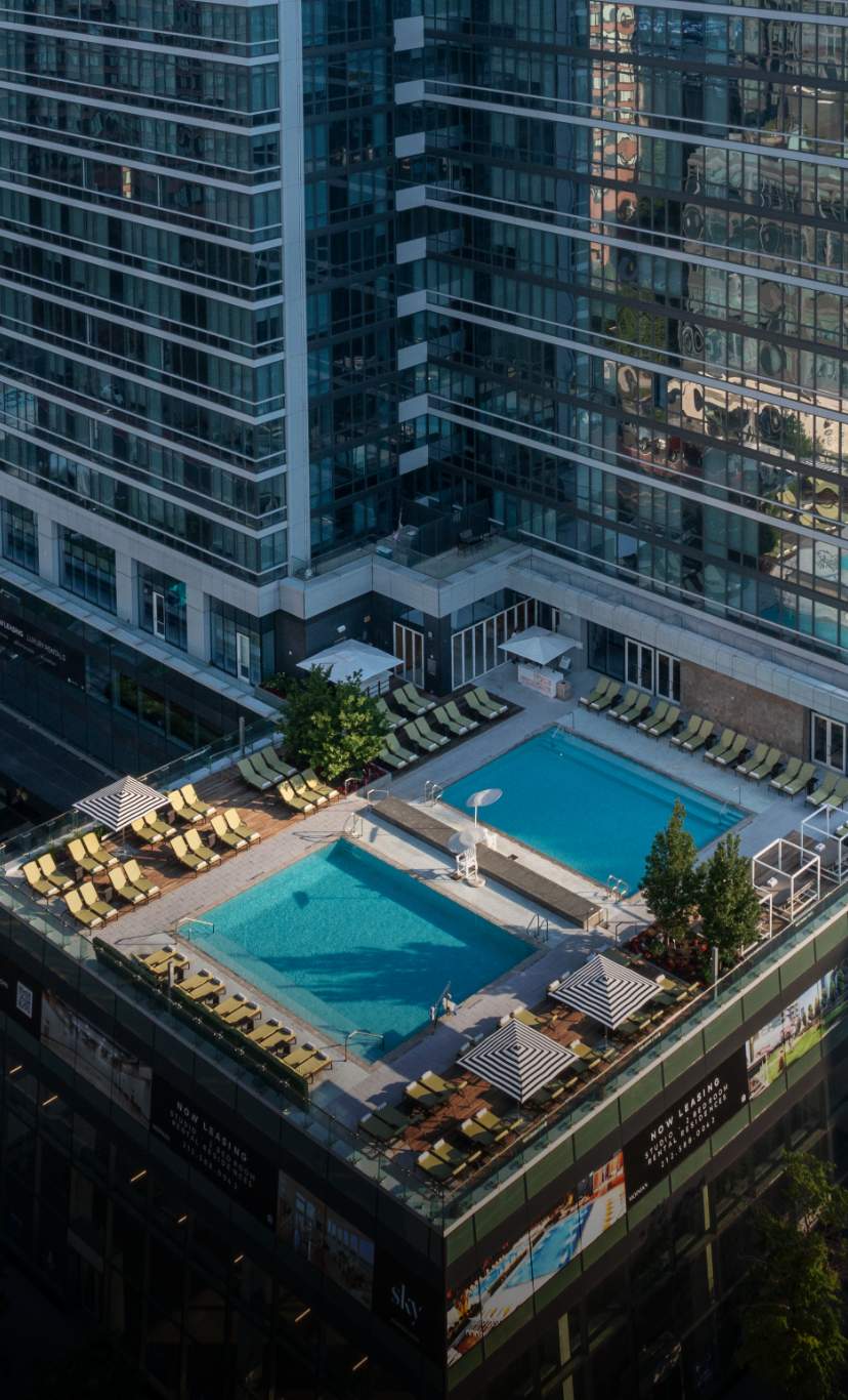 An aerial view of the rooftop pool area at Sky, amidst skyscrappers