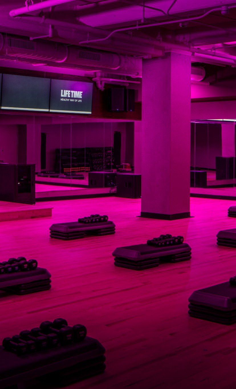 A dimly lit fitness studio with aerobics steps and weights
