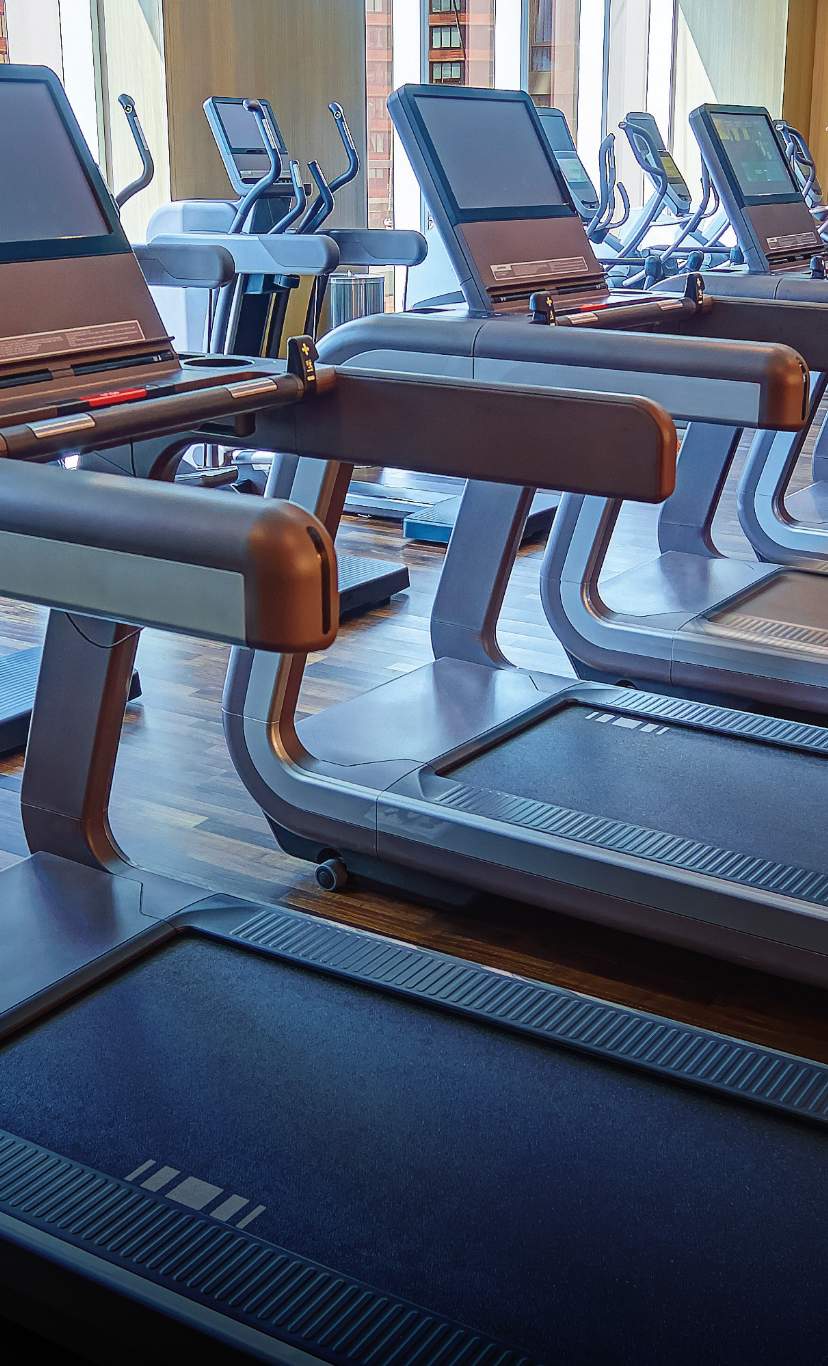 a man jogs on a treadmill, surrounded by many other treadmills